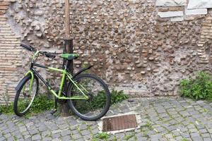 le vélo est enchaîné à un lampadaire sur un mur de briques. photo