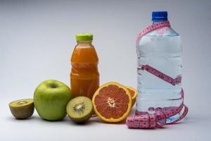 remise en forme féminine nature morte. aliments sains, fruits, jus et eau sur fond gris. photo