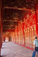 hue, vietnam - 08192015 - homme marchant seul dans le couloir du palais impérial, site du patrimoine mondial de l'unesco. rouge et doré.