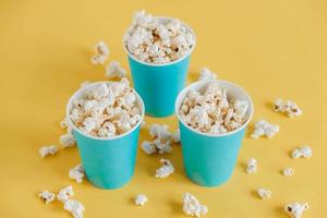 pop-corn dans des gobelets en papier bleus sur fond jaune. vue de dessus. copie, espace vide pour le texte photo