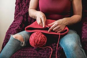 mains femme dans une maison confortable tricote à partir d'un fil rose. copie, espace vide pour le texte photo