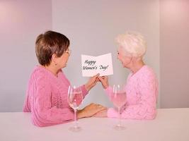 deux femmes matures buvant du vin et donnant une carte postale. amitié, vacances, amour, concept de mariage homosexuel photo