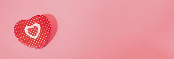 maquette de boîte en forme de coeur avec une ombre dure sur fond rose. espace de copie agrandi. photo