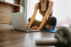 femme faisant de l'exercice à la maison et regardant des vidéos d'entraînement avec des haltères et regardant un ordinateur portable. photo