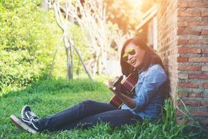 jeune fille hipster assise jouant de la guitare et chantant. photo