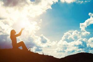 silhouette de femme priant sur fond de beau lever de soleil photo