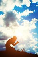 silhouette de femme priant sur fond de beau lever de soleil photo