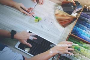 vue de dessus de deux collègues designers d'intérieur discutant des données avec une tablette numérique et un nouvel ordinateur portable moderne avec un échantillon de matériel sur un bureau en bois comme concept photo