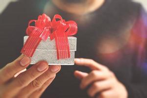 cadeaux, main d'homme tenant une boîte-cadeau dans un geste de donner. arrière-plan flou, effet bokeh photo