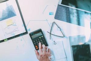 vue de dessus de la main d'homme d'affaires travaillant avec les finances sur le coût et la calculatrice et latop avec téléphone portable sur le bureau blanc dans un bureau moderne photo