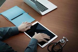 vue de dessus de la main du docteur en médecine travaillant avec un ordinateur moderne et une tablette numérique pro avec écran blanc sur un bureau en bois comme concept médical photo