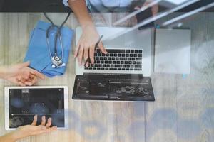 vue de dessus de la main du docteur en médecine travaillant avec un ordinateur moderne et une tablette numérique pro avec un diagramme médical numérique avec son équipe sur un bureau en bois comme concept médical photo