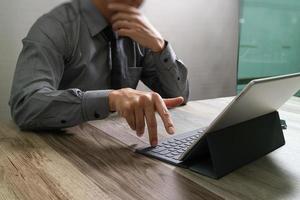 homme d'affaires travaillant avec un nouveau projet de démarrage. à l'aide d'un téléphone intelligent, d'une tablette numérique, d'un clavier intelligent et d'un ordinateur portable sur un bureau en bois, effet soleil photo