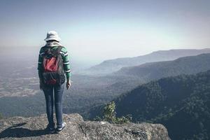 jeune femme touriste avec sac à dos debout vue sur la vallée du haut d'une montagne photo