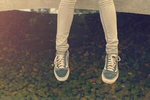 pieds de femme dans des baskets assis près du lac photo