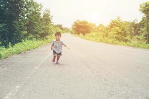heureux petit garçon en mouvement, smiley courant dans la rue. photo
