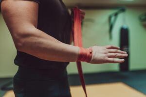 une Masculin main de boxeur ou combattant avec rouge boxe des pansements avant le bats toi ou formation dans sport salle de sport. photo