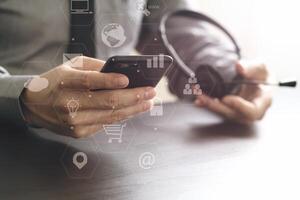 homme d'affaires utilisant un casque voip avec téléphone mobile et centre d'appels de communication concept sur un bureau en bois avec diagramme d'icône de réalité virtuelle photo