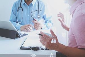 médecin utilisant un téléphone portable et consultant un homme d'affaires patient ayant un examen comme concept de professionnalisme hospitalier photo