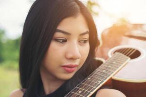 belle femme tenant une guitare sur son épaule, parc naturel été à l'extérieur. photo