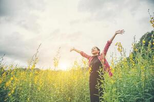 belle jeune femme debout dans le plaisir du champ de fleurs. photo