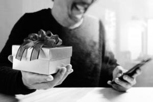 cadeau donnant la main créative en choisissant et la main avec un cadeau. livraison de cadeaux, surprise, utilisation d'un téléphone intelligent sur un bureau mable, effet de film filtrant photo