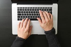 vue de dessus d'un homme d'affaires tapant du clavier avec un ordinateur portable sur un bureau en bois dans un bureau moderne photo