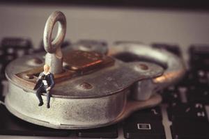 concept de sécurité internet-homme d'affaires miniature debout sur l'ancienne clé et cadenas sur le clavier de l'ordinateur portable photo