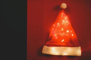 concept de saison de salutation.chapeau de père noël avec lumière de noël sur fond rouge et vert photo