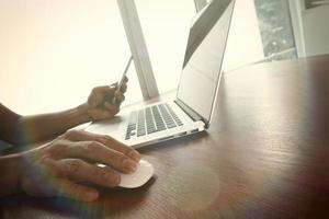 main d'homme d'affaires travaillant sur un ordinateur portable sur un bureau en bois photo