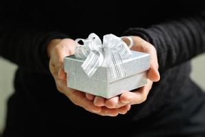 cadeaux, main d'homme tenant une boîte cadeau dans un geste de donner. arrière-plan flou, effet bokeh, vintage photo