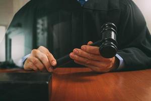 concept de justice et de droit. juge masculin dans une salle d'audience frappant le marteau, travaillant avec un clavier d'accueil d'ordinateur tablette numérique sur une table en bois, effet de filtre photo