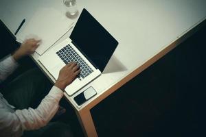 vue de dessus d'un homme travaillant avec des documents commerciaux sur une table de bureau avec une tablette numérique et un homme travaillant avec un ordinateur portable intelligent photo