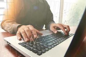 Homme d'affaires travaillant à la main sur un ordinateur portable sur un bureau en bois comme concept avec effet d'exposition couvert photo