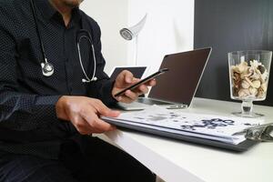 médecin intelligent travaillant avec un téléphone intelligent et une tablette numérique et un ordinateur portable et un stéthoscope sur un bureau en bois dans un bureau moderne photo