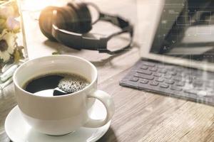 tasse à café et clavier intelligent de dock de table numérique, herbes de fleurs de vase, casque de musique, lunettes sur la table en bois, effet de filtre photo