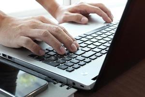 gros plan sur une main d'homme d'affaires travaillant sur un ordinateur portable sur un bureau en bois comme concept photo