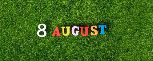 8 août. image de lettres et de chiffres colorés en bois le 8 août sur fond de pelouse verte, journée mondiale du chat. un jour d'été. photo