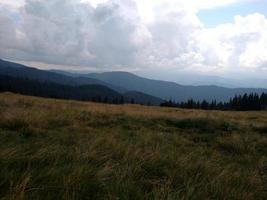 les montagnes ont mangé des nuages et des pelouses avec de l'herbe sèche photo