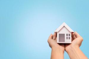 main tenant les clés et le modèle de maison sur fond bleu pour le plan de refinancement et le concept immobilier. photo
