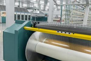 le fil textile sur la machine d'emballage est vissé sur le grand arbre. machines et équipements dans une usine textile photo