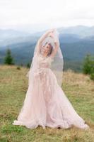 belle mariée posant dans sa robe de mariée sur fond de montagnes. photo