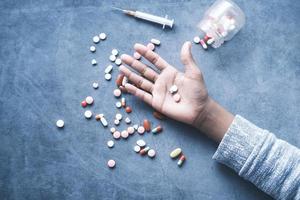 concept de toxicomanie avec la main tenant des pilules et une seringue posée sur le sol photo