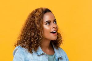 portrait en gros plan d'une surprenante jeune belle femme afro-américaine regardant vers le haut dans un studio isolé sur fond jaune photo