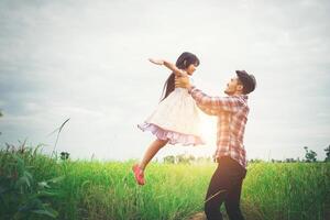 papa portant sa fille avec la nature et la lumière du soleil, famille de plaisir. photo