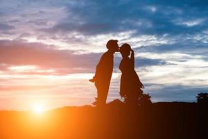silhouette de doux couple s'embrassant sur fond de coucher de soleil. photo