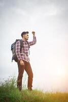 portrait de jeune homme hipster en plein air levant les mains avec sac à dos sur son épaule, tourisme d'aventure. photo