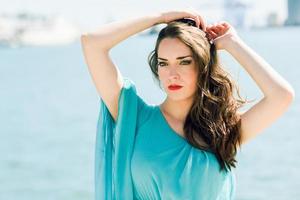 femme aux yeux bleus vêtue d'une robe bleue à la plage. photo