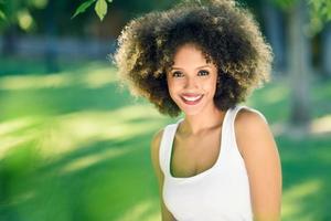 jeune femme noire avec une coiffure afro souriante dans un parc urbain photo