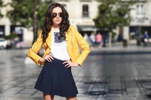 jeune femme brune avec des lunettes de soleil en milieu urbain photo